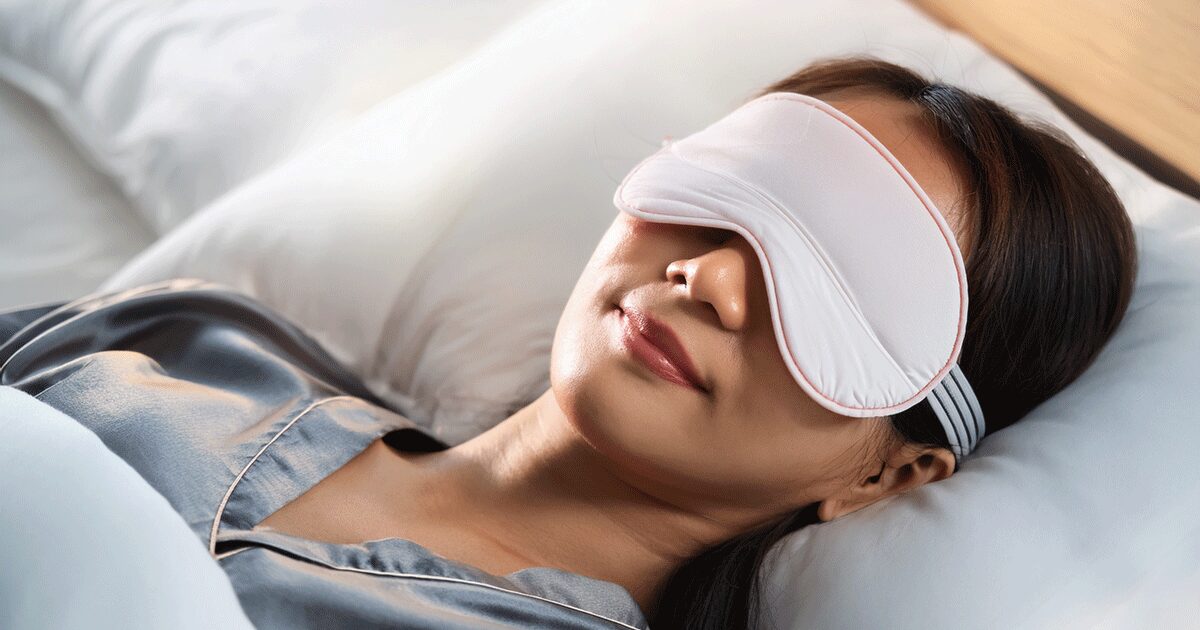 アイマスクを着用し、ベッドで睡眠している女性